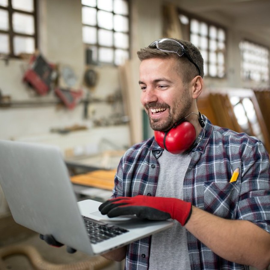 Trabajador de taller usando laptop para gestionar su negocio